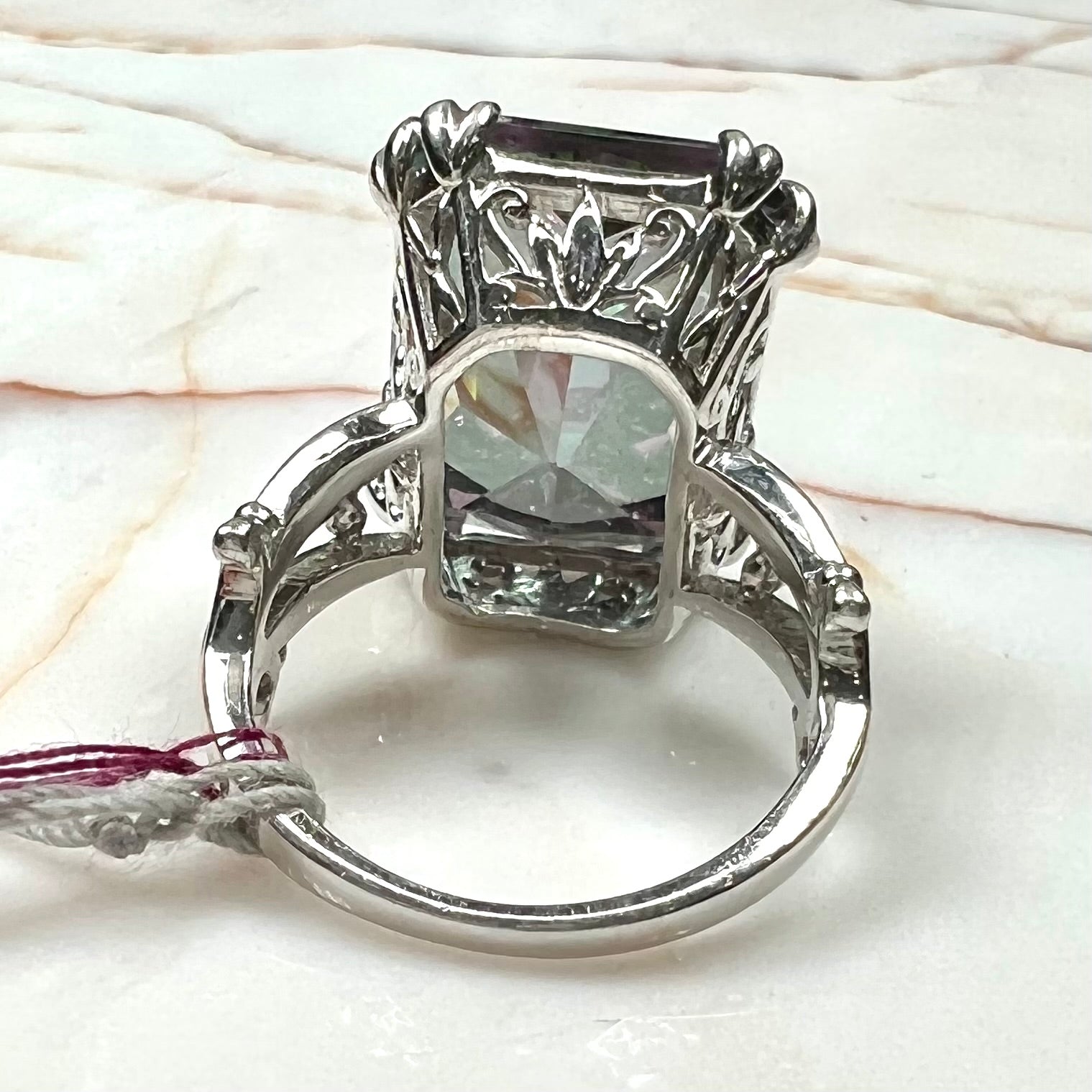 Emerald cut mystic topaz prong set in a decorative sterling silver ring.