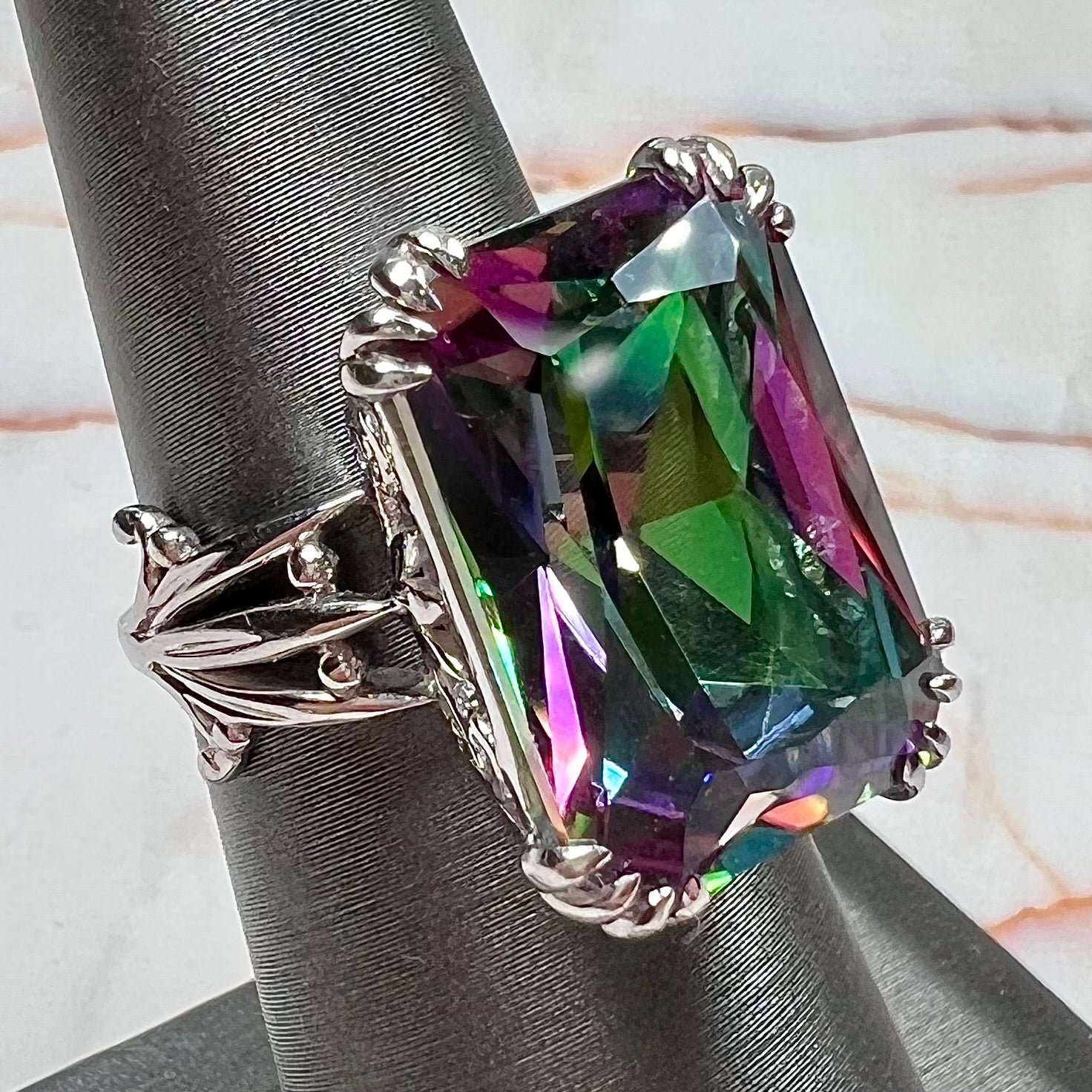 Emerald cut mystic topaz prong set in a decorative sterling silver ring.