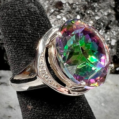 A large, round cut pink and green mystic topaz set in a sterling silver ring with white topaz accent stones.