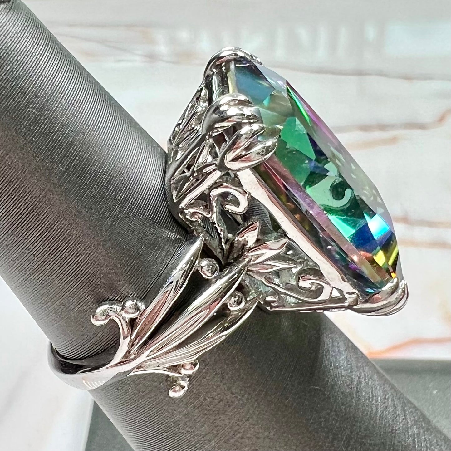 Emerald cut mystic topaz prong set in a decorative sterling silver ring.