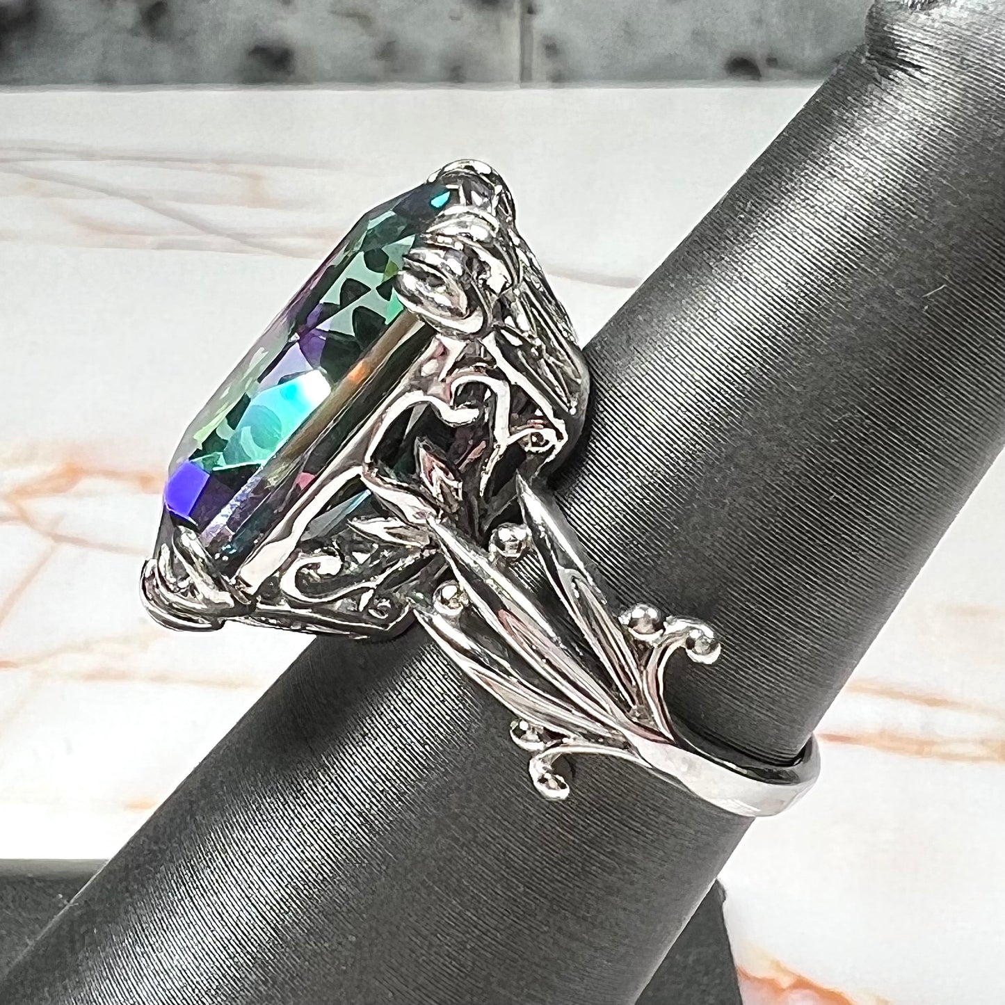 Emerald cut mystic topaz prong set in a decorative sterling silver ring.