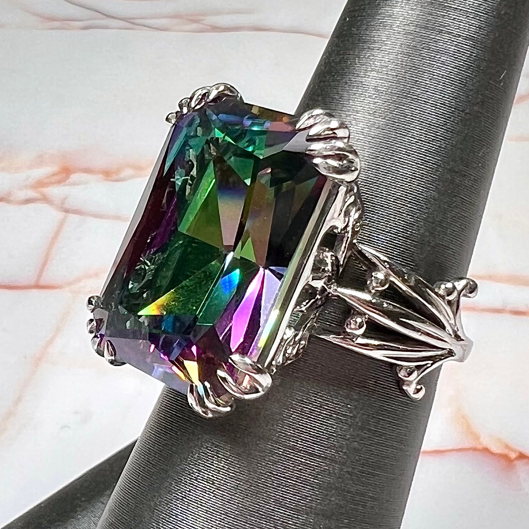 Emerald cut mystic topaz prong set in a decorative sterling silver ring.
