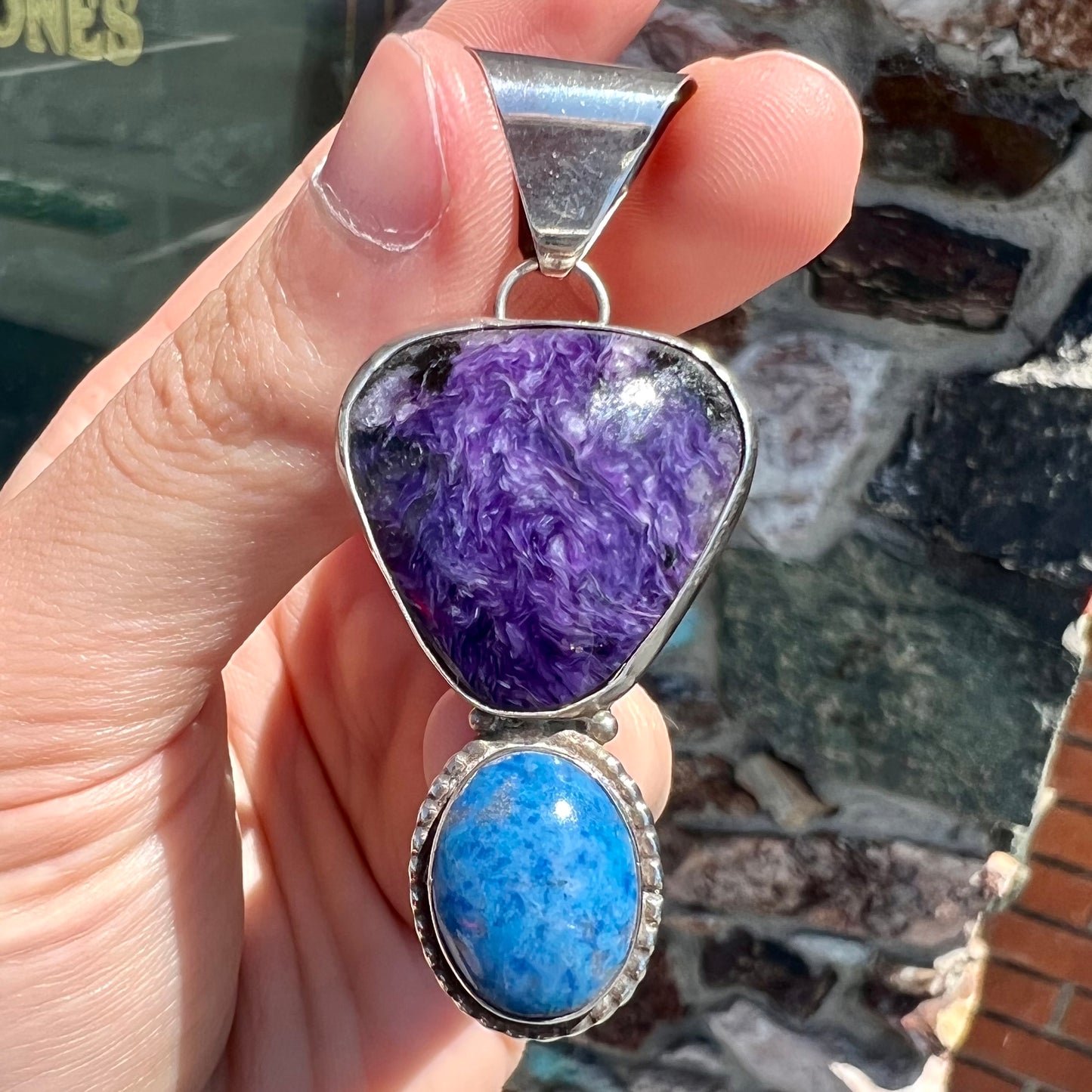 A sterling silver pendant set with polished charoite and lapis lazuli stones, hand signed "KK" by the artist.