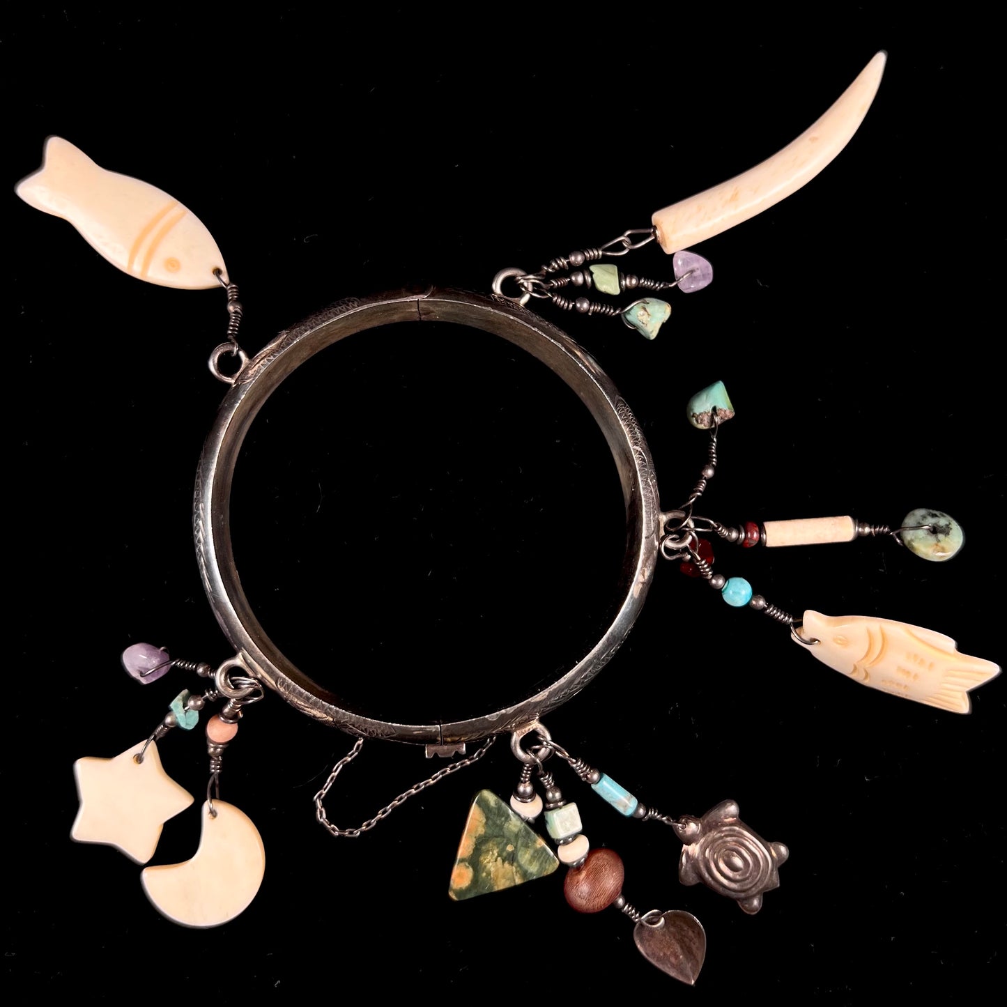 A Native American sterling silver bangle bracelets attached with carved bone, gemstone, and silver charm fetishes.
