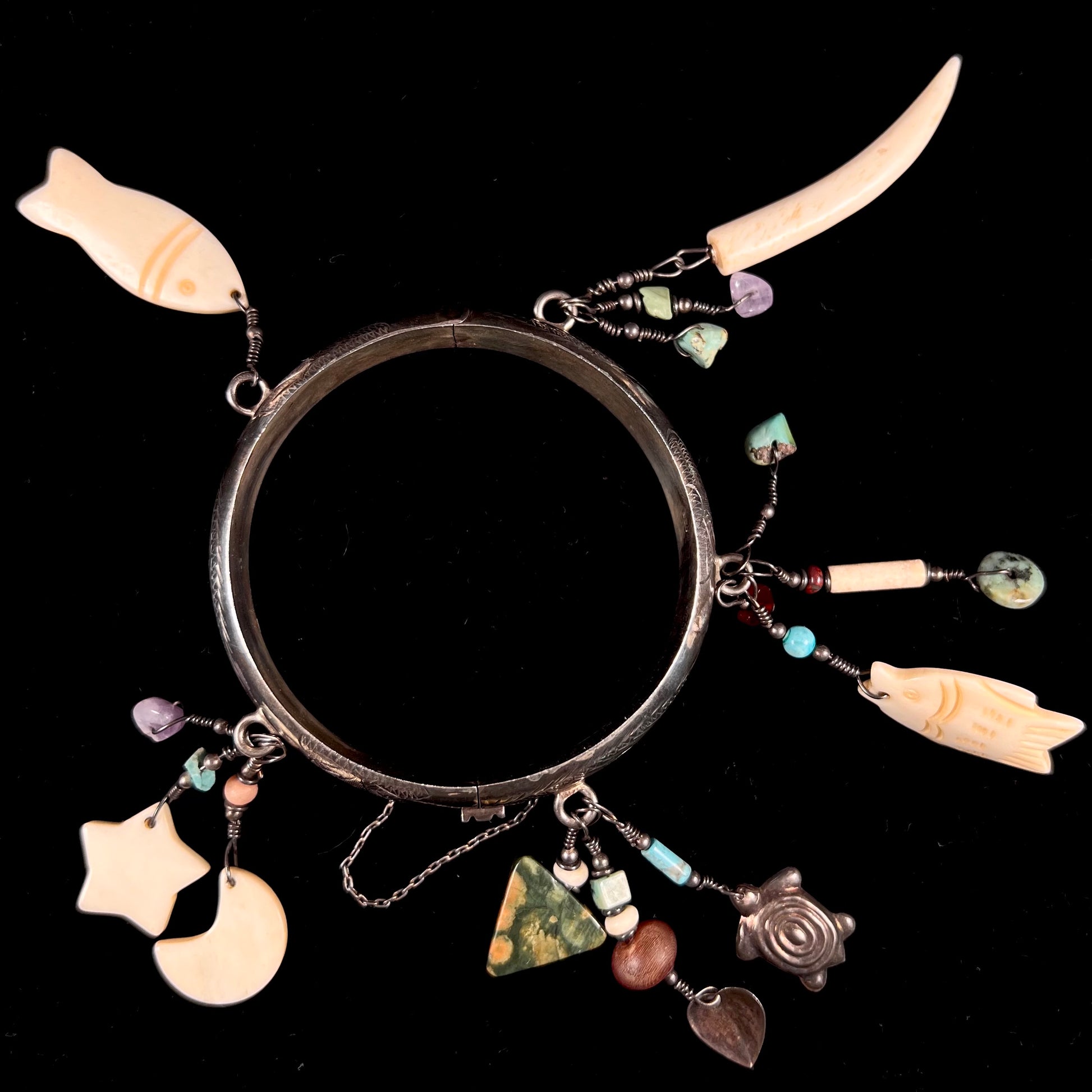 A Native American sterling silver bangle bracelets attached with carved bone, gemstone, and silver charm fetishes.