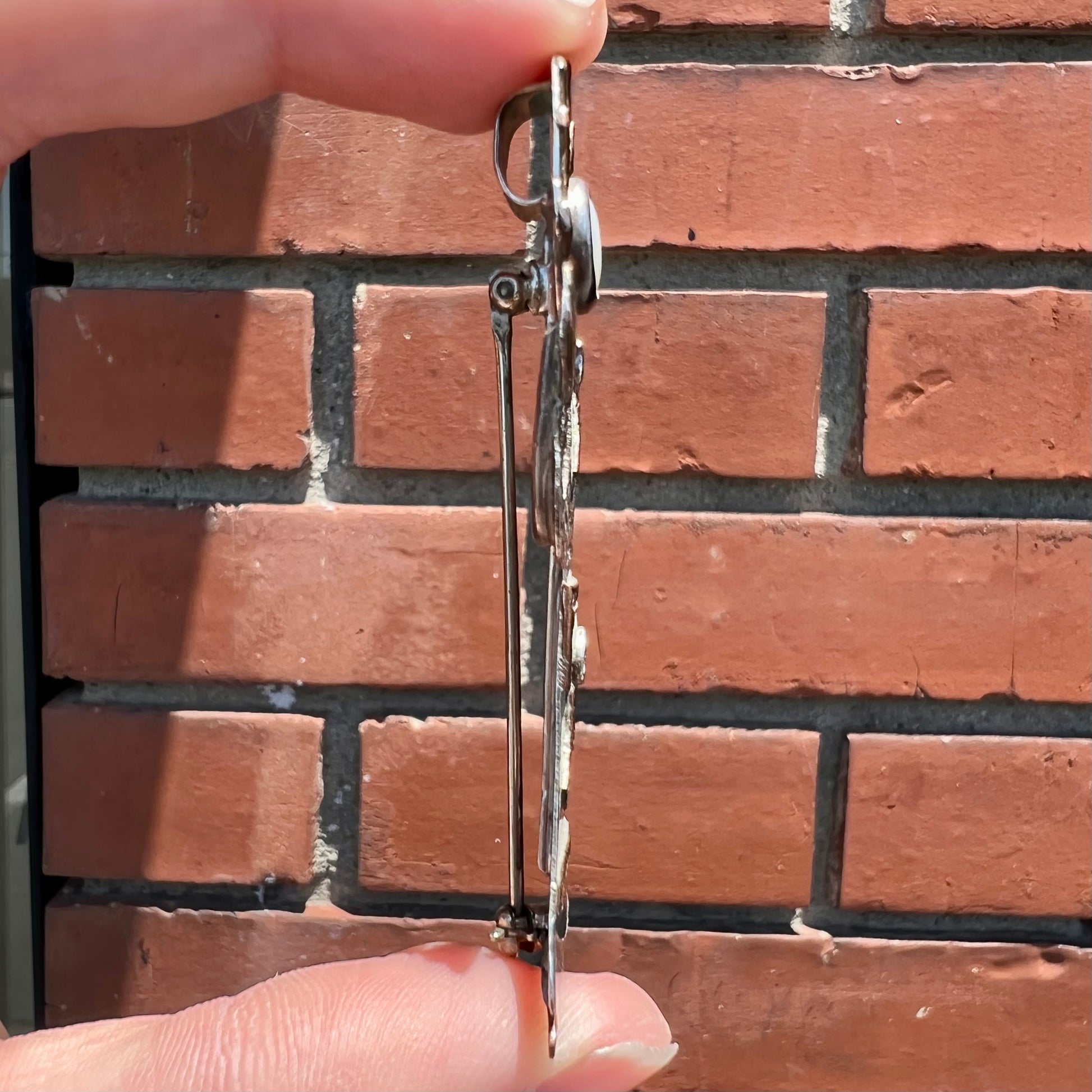 A handmade Navajo style silver pendant with copper highlights shaped like a Navajo Indian shaman.  There is a mother of pearl set as the shaman's face.