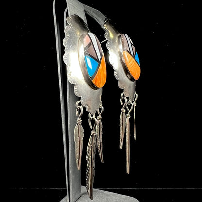 A pair of Native American style feather dangle earrings inlaid with mother of pearl shell and turquoise.