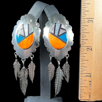 A pair of Native American style feather dangle earrings inlaid with mother of pearl shell and turquoise.