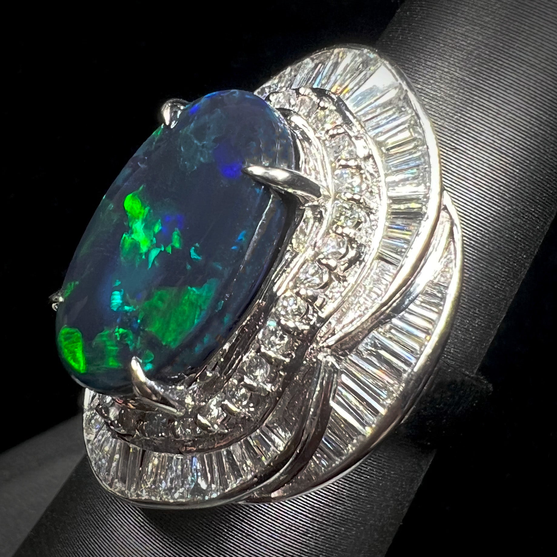 A ladies' platinum diamond halo ring set with a natural black opal stone from Lightning Ridge, Australia.