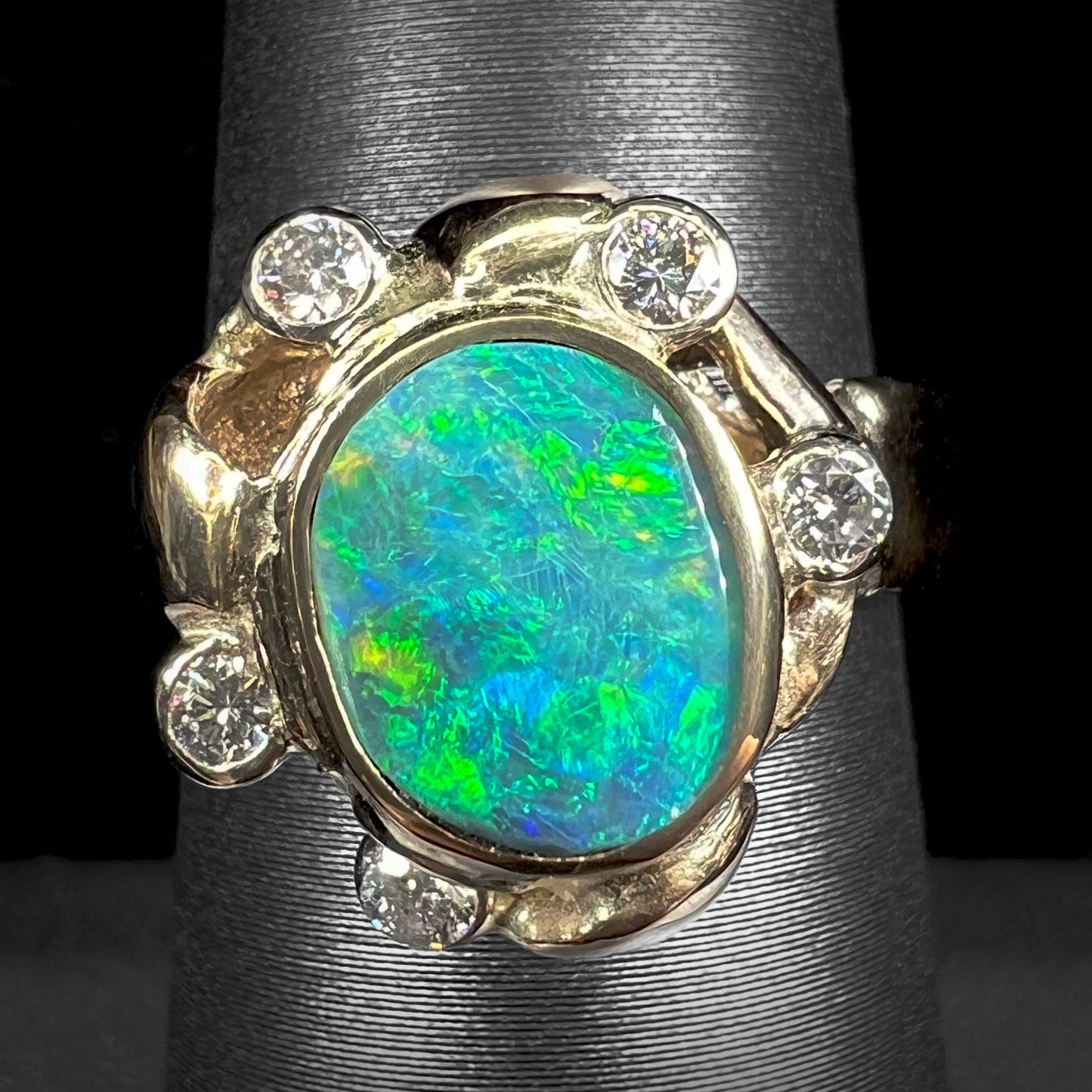 A ladies' yellow gold oval cut natural black opal ring set with five round accent diamonds.