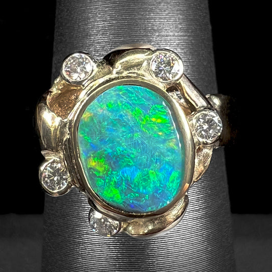 A ladies' yellow gold oval cut natural black opal ring set with five round accent diamonds.