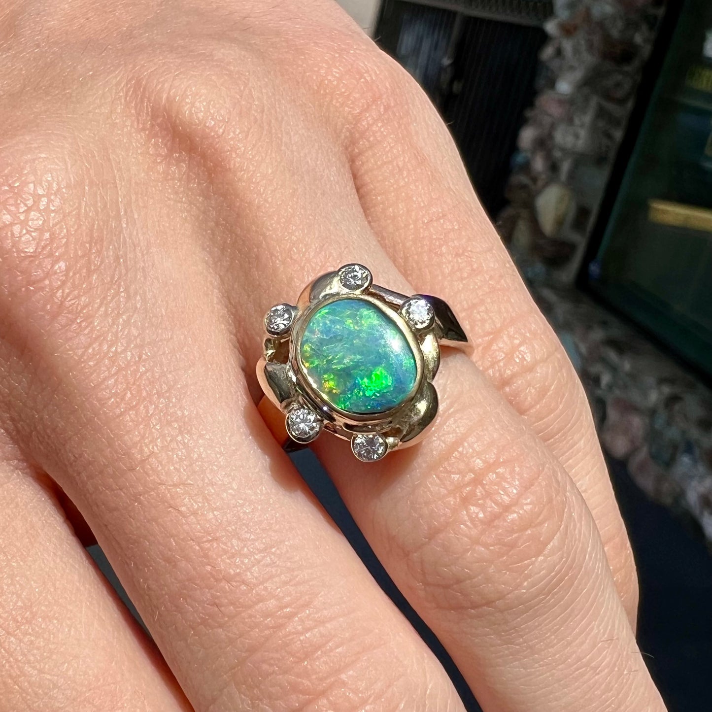 A ladies' yellow gold oval cut natural black opal ring set with five round accent diamonds.