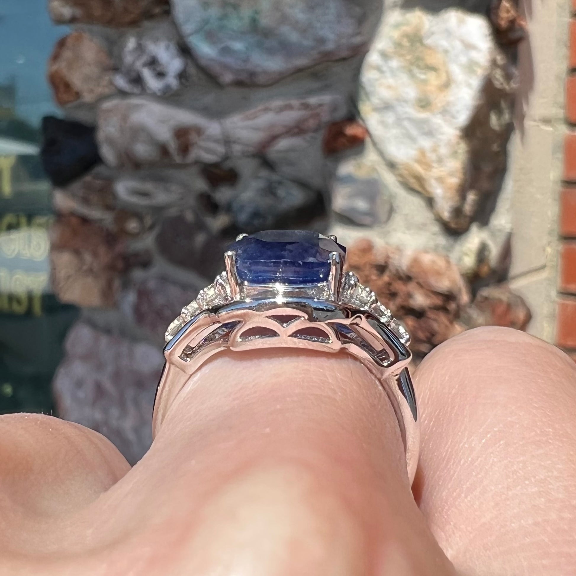 A sterling silver ring set with a cushion cut blue sapphire center stone and round cut white sapphire accents.