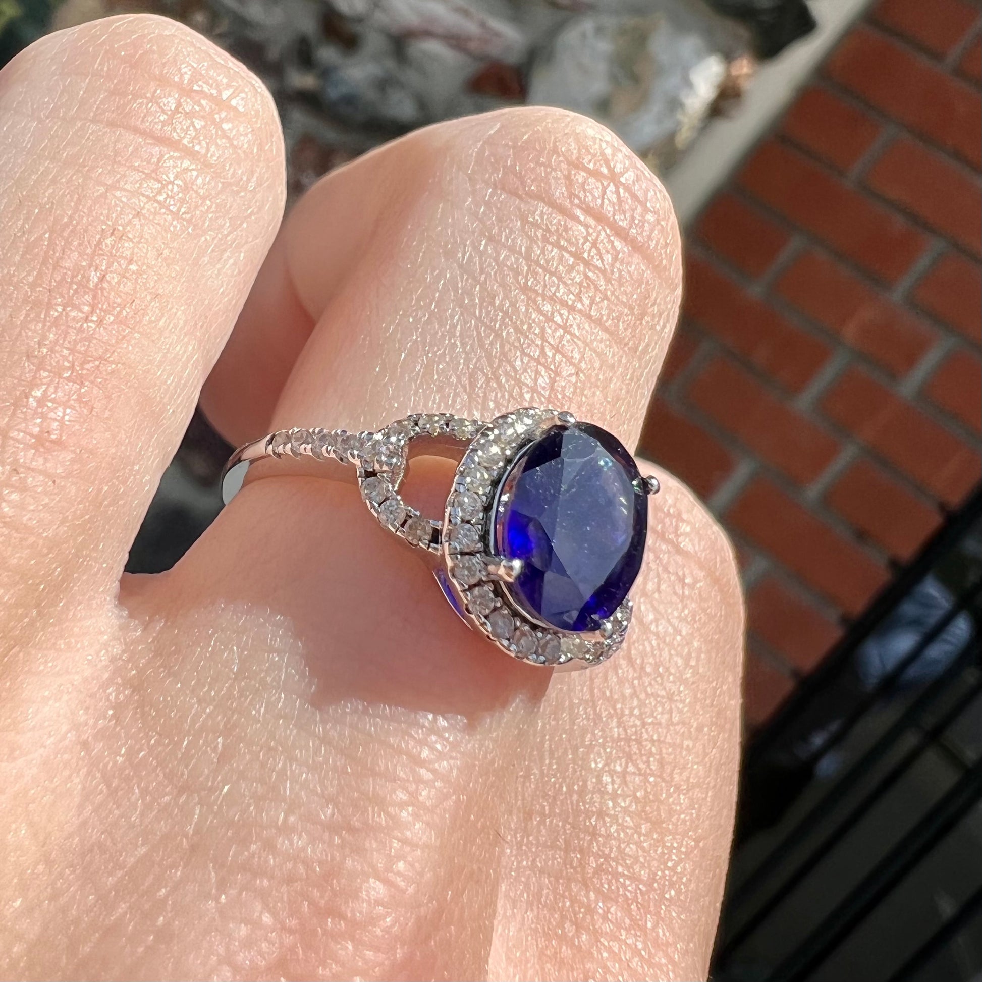 A sterling silver, white zircon halo ring set with an oval cut blue sapphire.