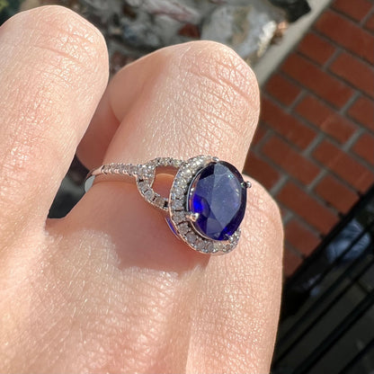 A sterling silver, white zircon halo ring set with an oval cut blue sapphire.
