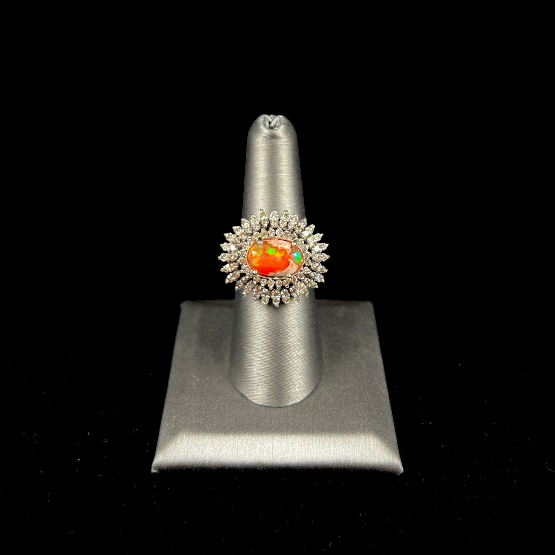 An 18k white gold orange fire opal ring set with a triple halo of diamonds.