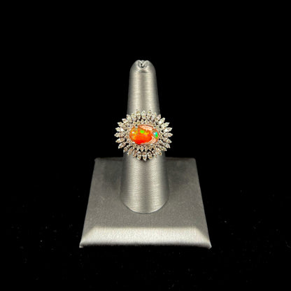 An 18k white gold orange fire opal ring set with a triple halo of diamonds.