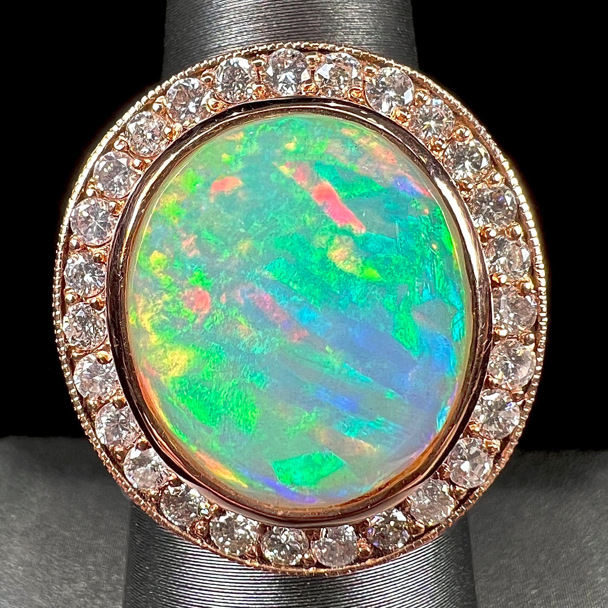 A ladies' natural crystal fire opal ring set in rose gold with a halo of round cut diamonds.