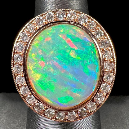 A ladies' natural crystal fire opal ring set in rose gold with a halo of round cut diamonds.