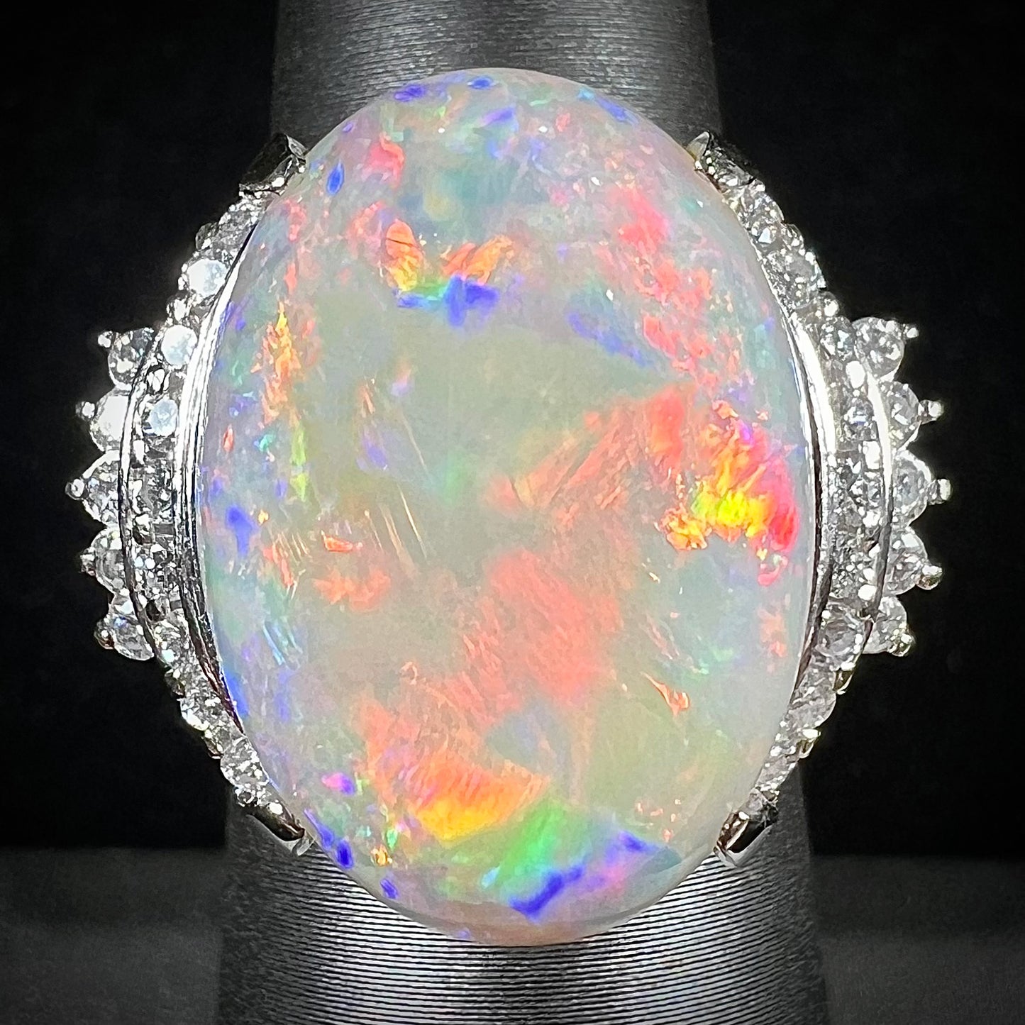 An oval cabochon cut Coober Pedy, Australian opal prong set in a platinum ring with round cut diamonds.