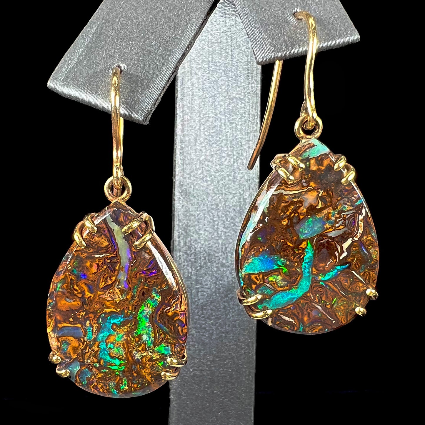 A pair of ladies' yellow gold dangle earrings set with pear shaped natural boulder opal stones from Koroit, Australia.