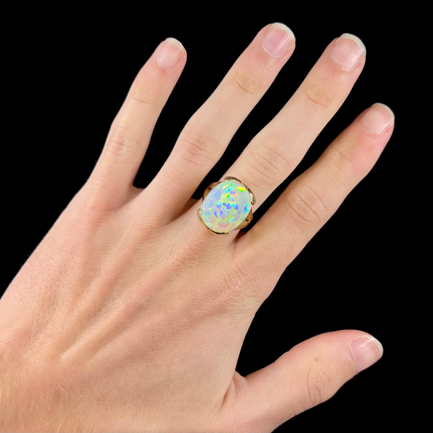A ladies' yellow gold split shank ring half-bezel set with a barrel cabochon cut natural Ethiopian fire opal stone.