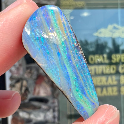 A loose, polished, freeform drop shaped boulder opal stone from Quilpie, Australia.
