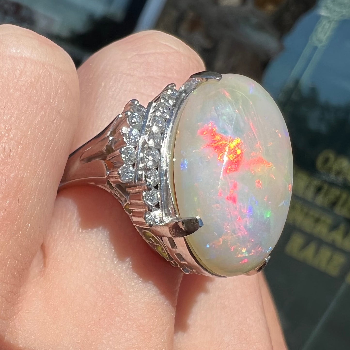 An oval cabochon cut Coober Pedy, Australian opal prong set in a platinum ring with round cut diamonds.