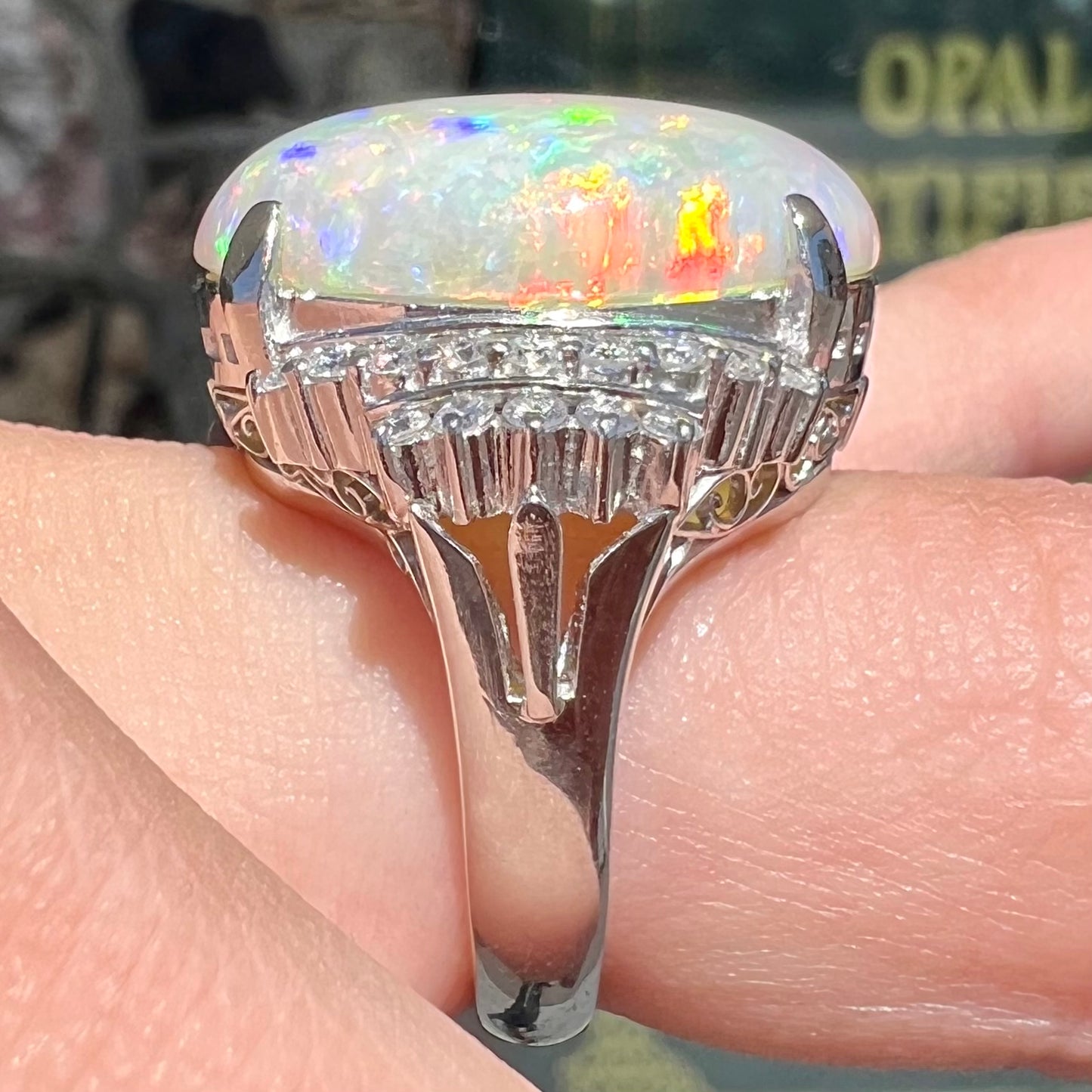 An oval cabochon cut Coober Pedy, Australian opal prong set in a platinum ring with round cut diamonds.