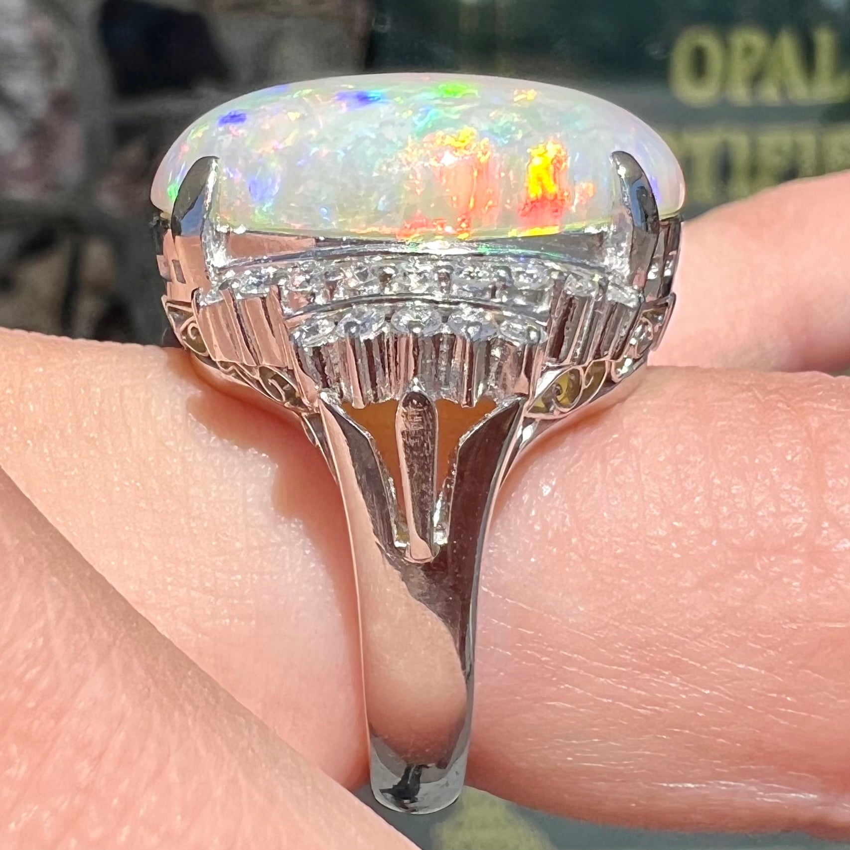 An oval cabochon cut Coober Pedy, Australian opal prong set in a platinum ring with round cut diamonds.