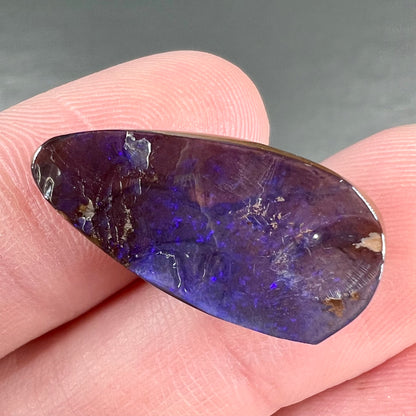 A loose, teardrop shaped purple boulder opal stone.
