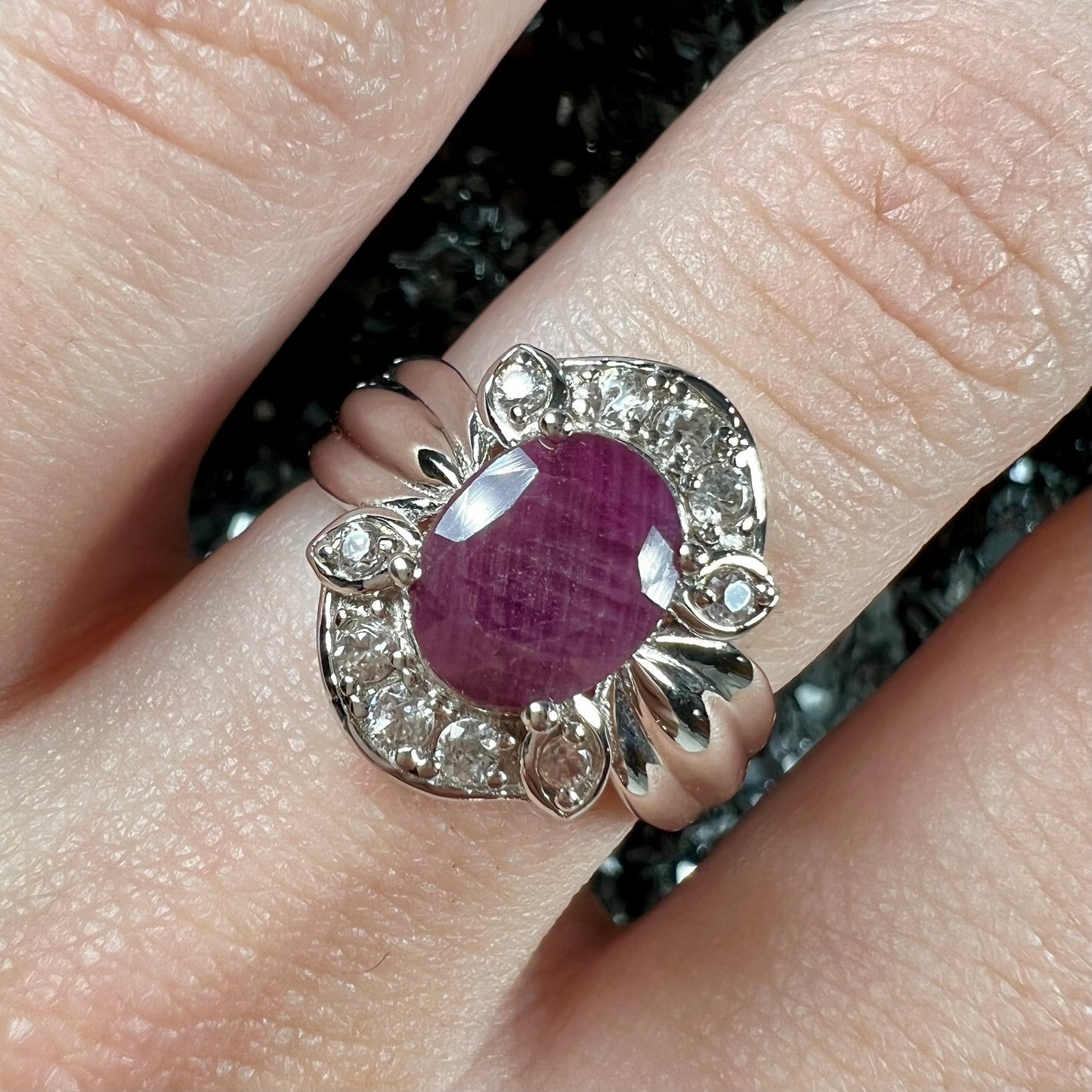 A natural, faceted oval cut ruby ring cast in sterling silver and set with cubic zirconia accents.