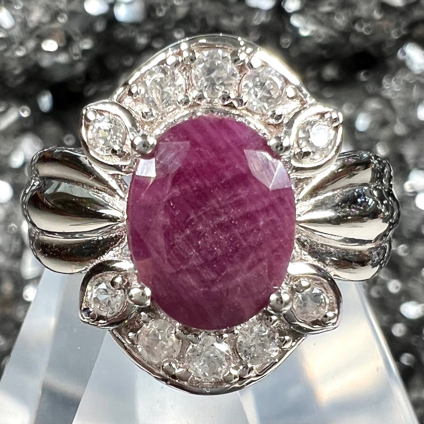 A natural, faceted oval cut ruby ring cast in sterling silver and set with cubic zirconia accents.