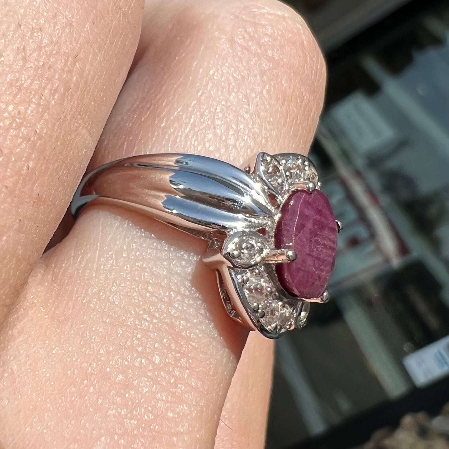 A natural, faceted oval cut ruby ring cast in sterling silver and set with cubic zirconia accents.