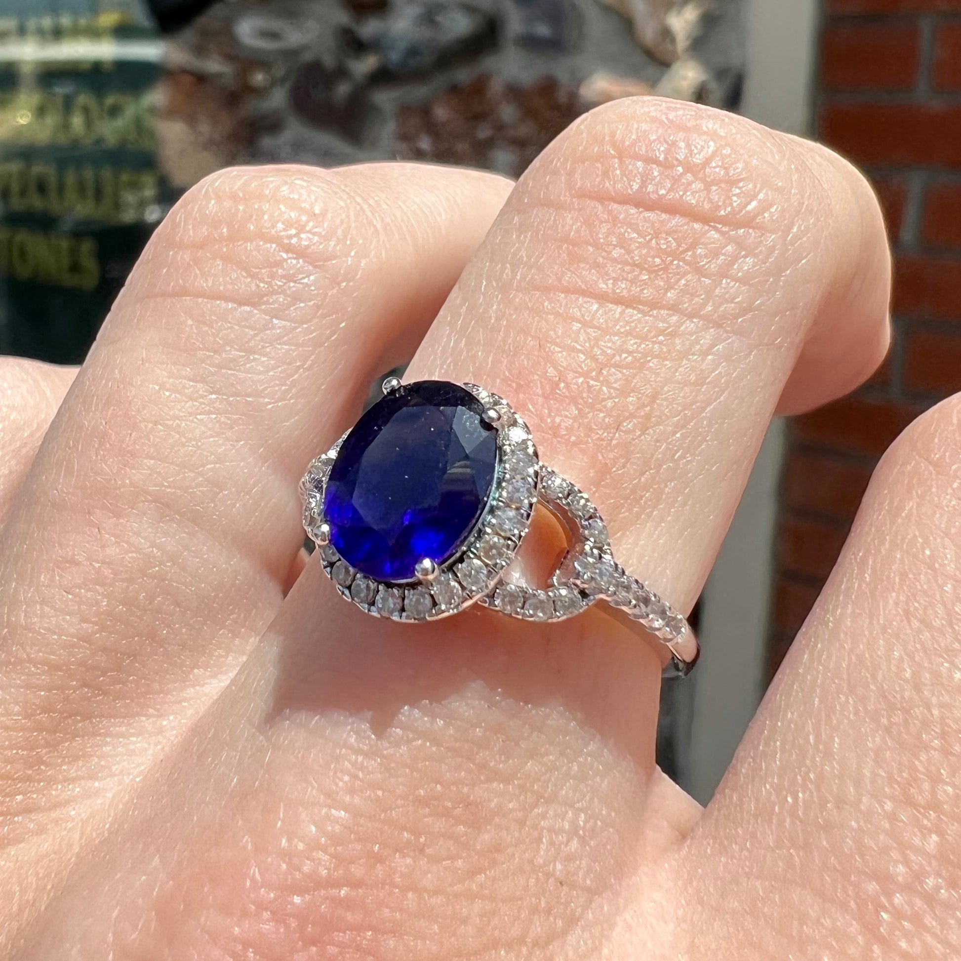 A sterling silver, white zircon halo ring set with an oval cut blue sapphire.