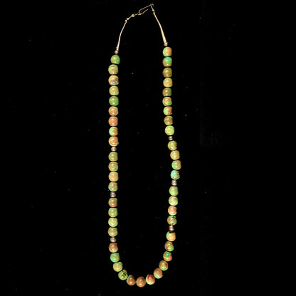 A handmade, likely Navajo silver pendant set with Kingman turquoise on a green Kingman turquoise beaded necklace.