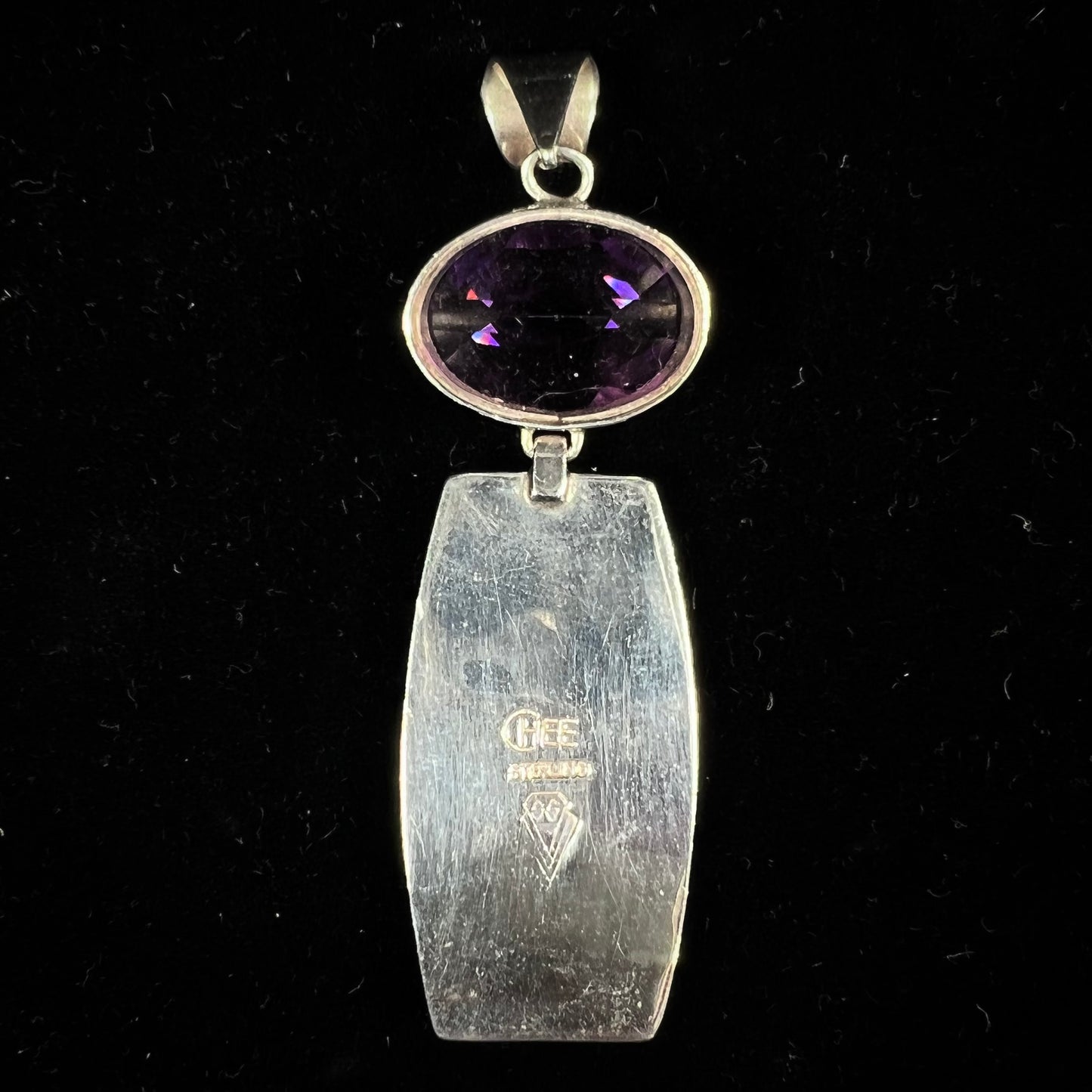 A sterling silver stone inlay necklace set with amethyst, sugilite, spiderweb turquoise, and lab created opal by Navajo artist, Peterson Chee.