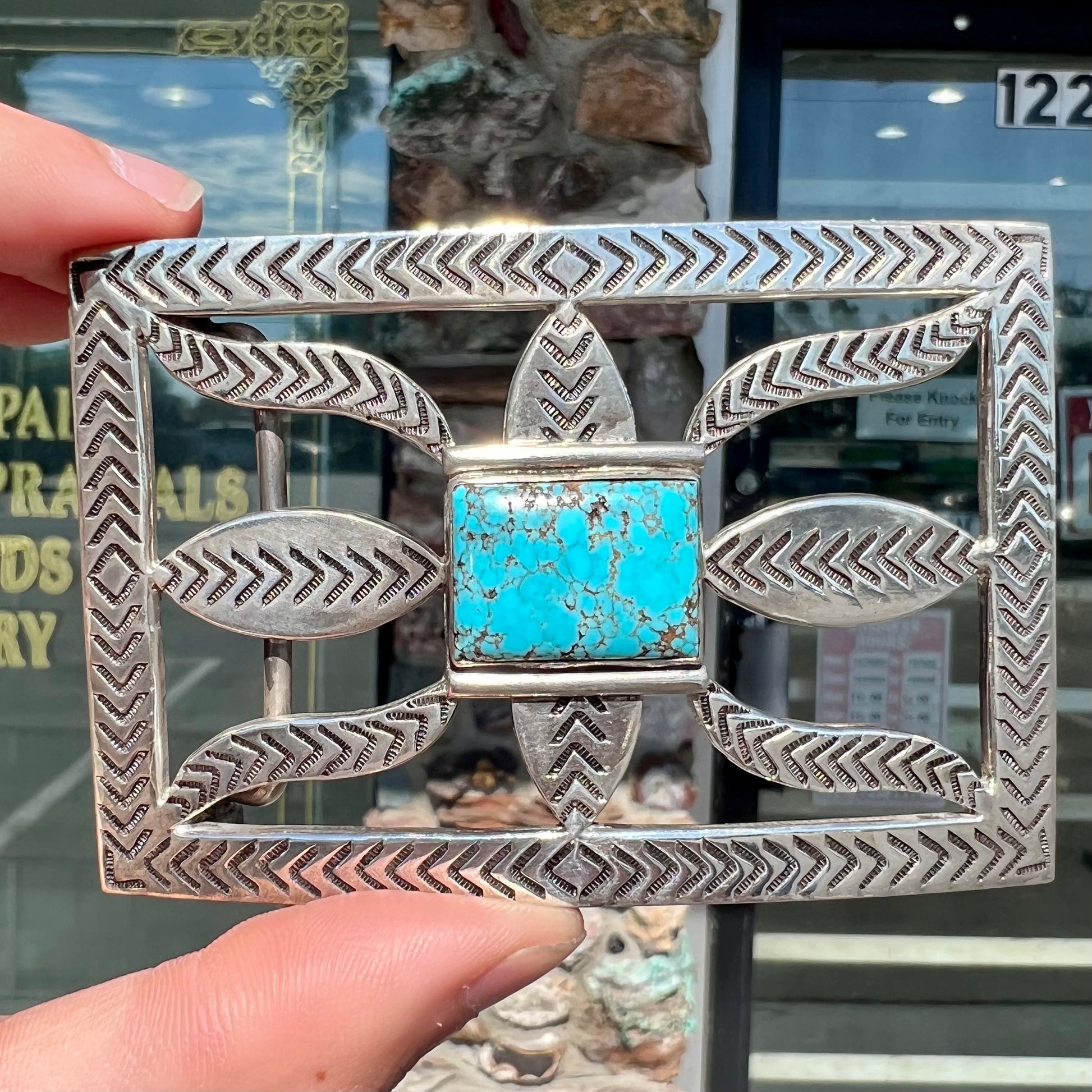 A handmade, Navajo style, sterling silver belt buckle set with a rectangular cabochon cut blue turquoise.