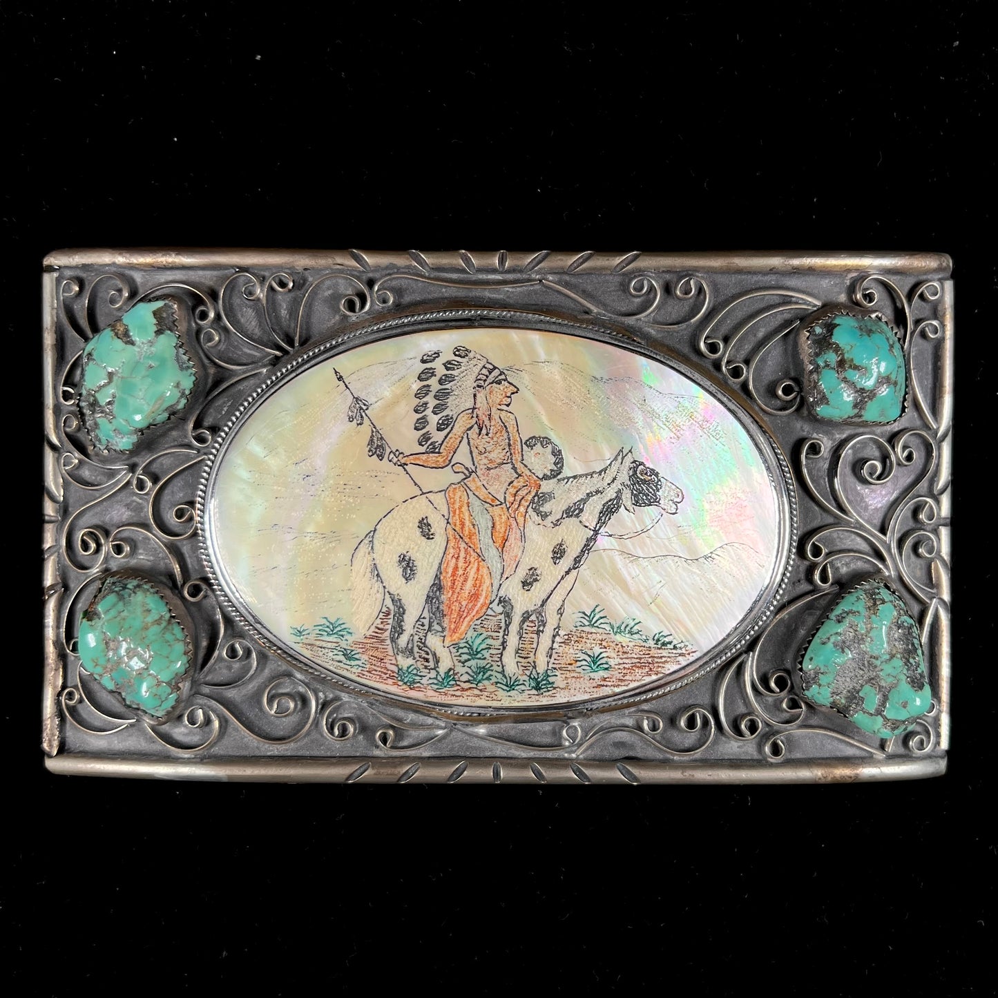 A men's Navajo-made white brass belt buckle set with turquoise nuggets and a mother of pearl stone etched with a Native American riding a horse.