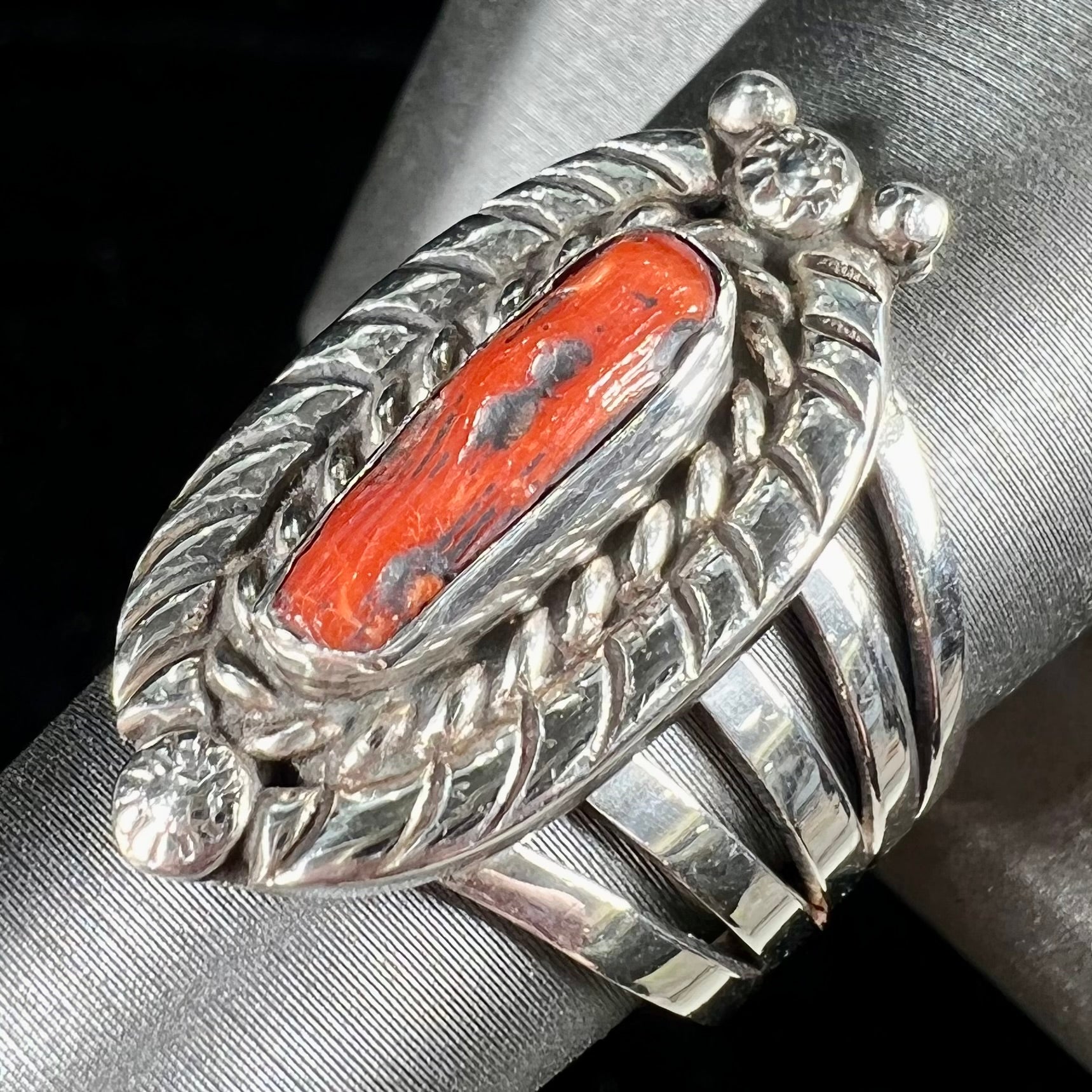 A sterling silver ring set with a polished red coral branch handmade by Navajo artist, Delbert Chatter.