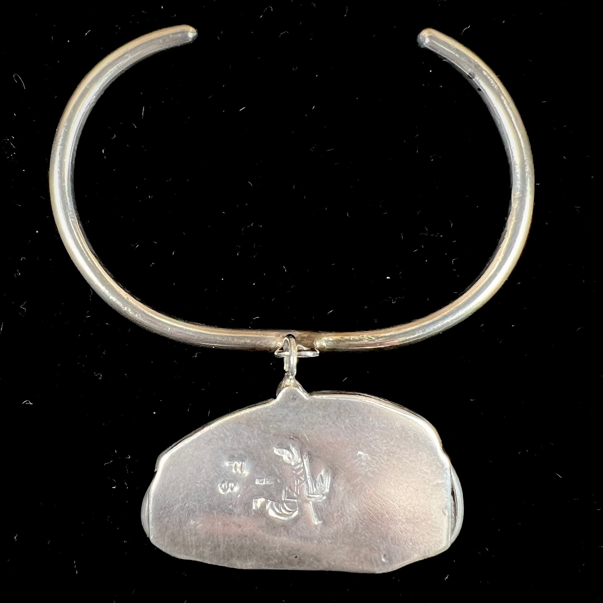 A sterling silver cuff bracelet with an attached dangle segment set with a turquoise stone from Pinto Valley.