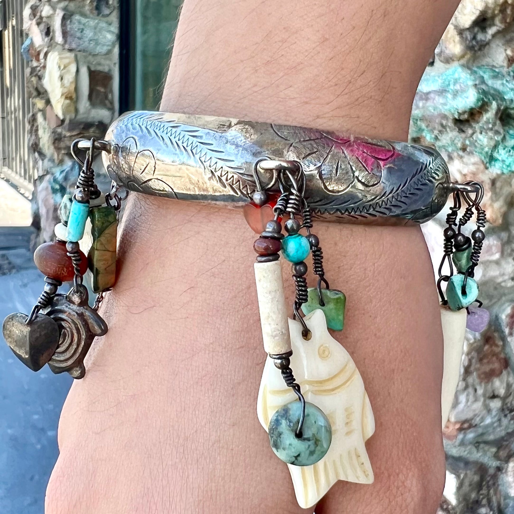 A Native American sterling silver bangle bracelets attached with carved bone, gemstone, and silver charm fetishes.