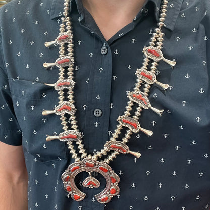 A Navajo style squash blossom necklace set with red coral branches, handmade by artist Delbert Chatter.
