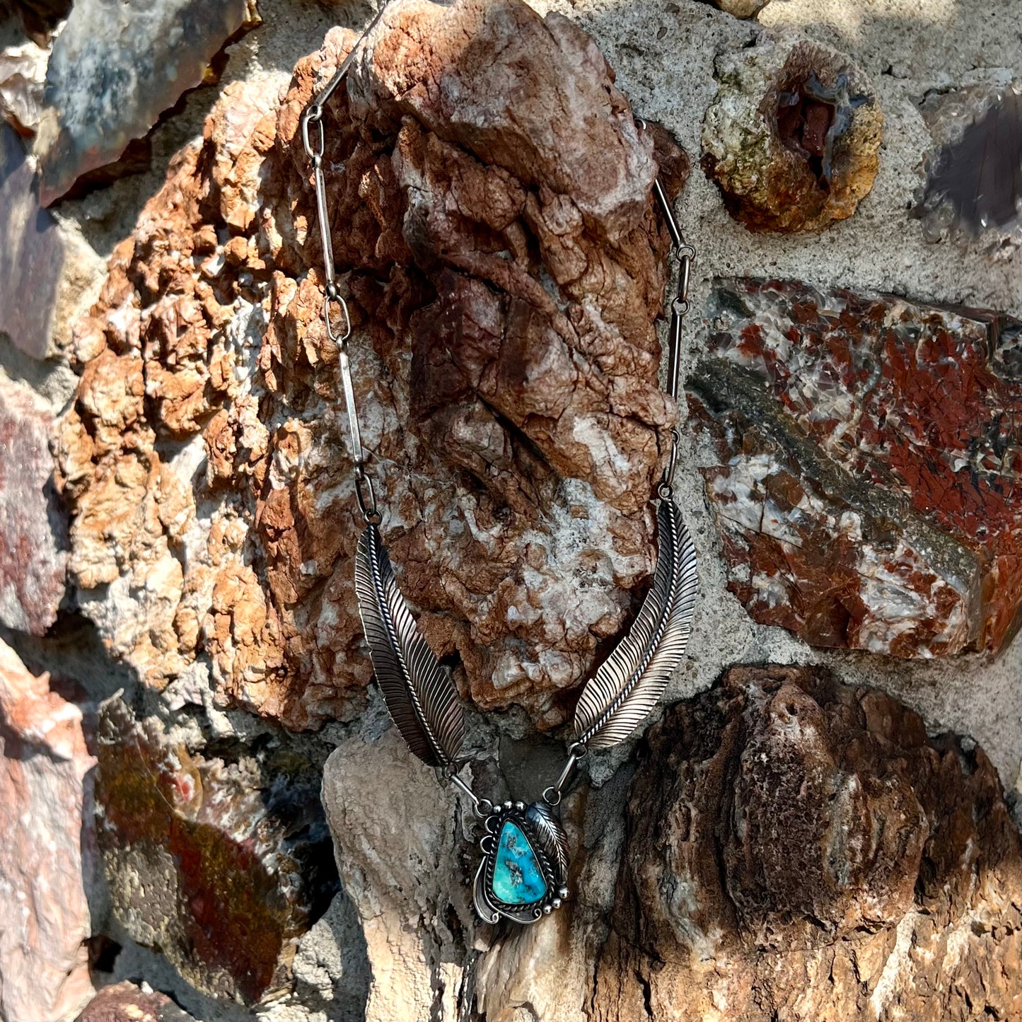 A sterling silver feather motif necklace set with a Sleeping Beauty turquoise stone, handmade by Navajo artist, Jameson Lee.