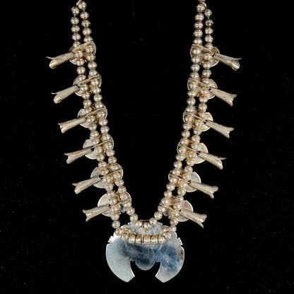 A silver Kingman turquoise squash blossom necklace.  The necklace is made with handmade Navajo pearls.
