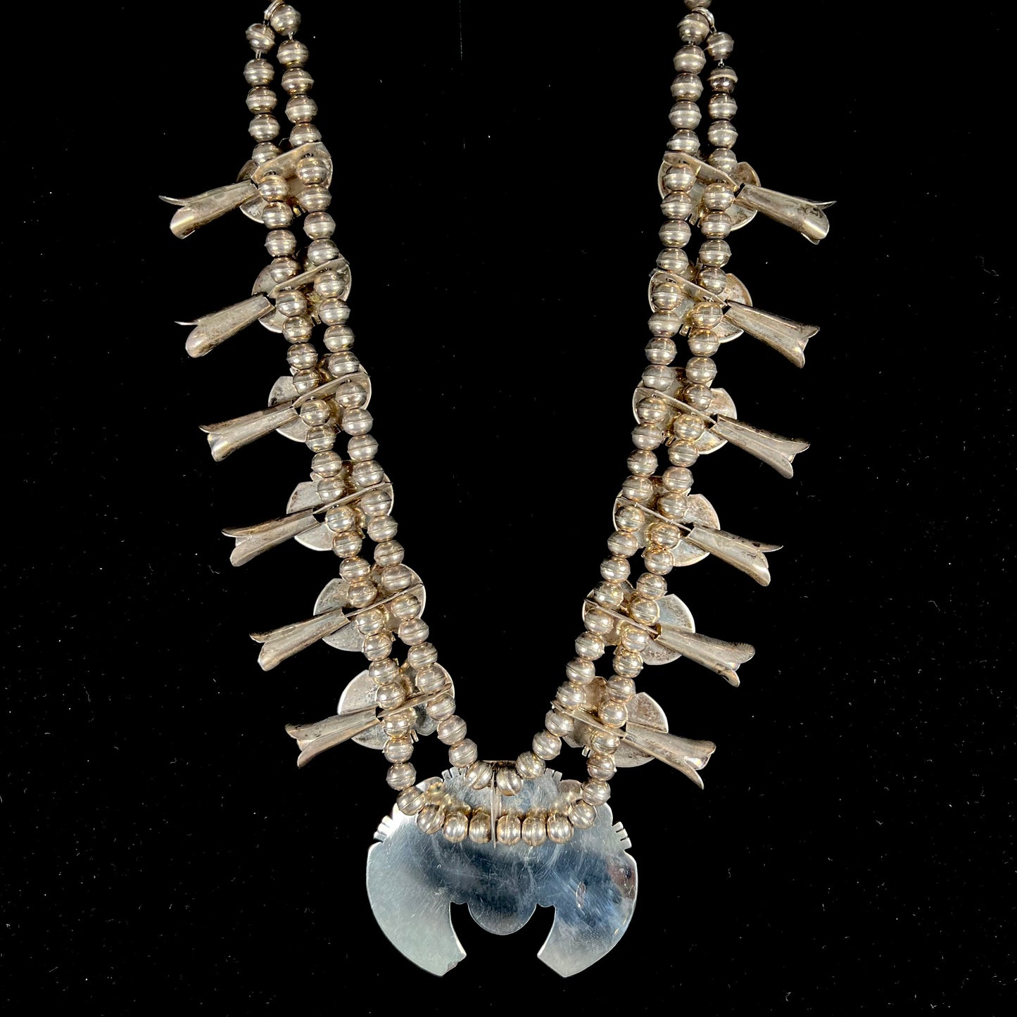 A silver Kingman turquoise squash blossom necklace.  The necklace is made with handmade Navajo pearls.