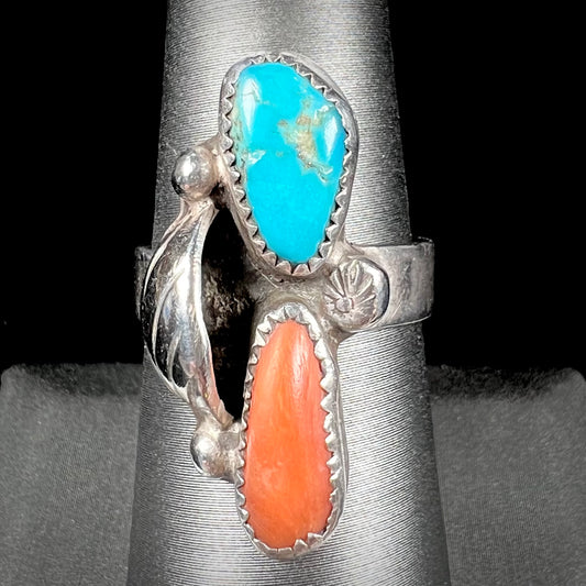 A Navajo silver ring set with turquoise and coral stones.  The ring has a feather decoration.