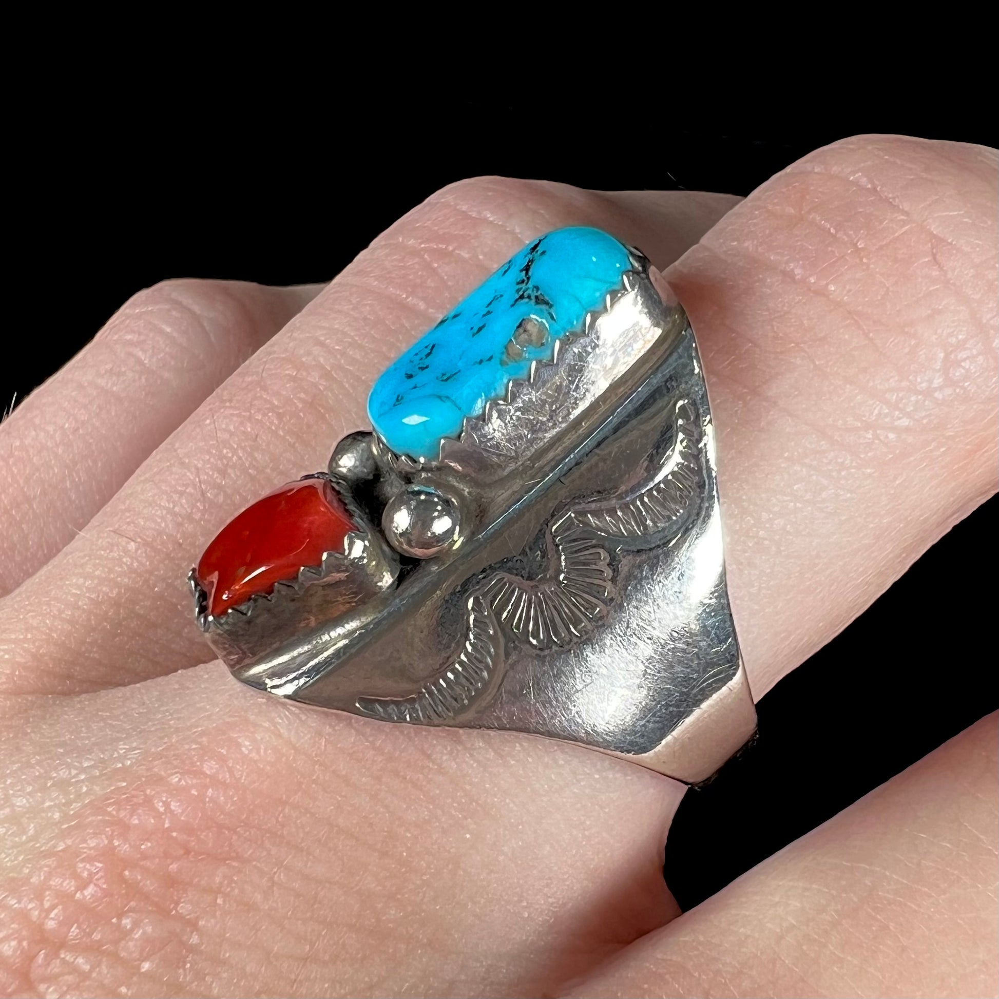 A men's sterling silver Navajo ring set with turquoise and red coral stones.