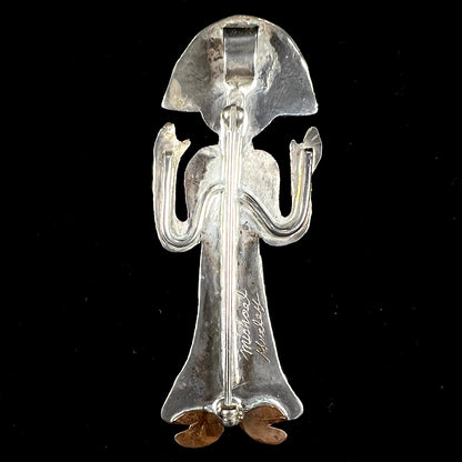 A handmade Navajo style silver pendant with copper highlights shaped like a Navajo Indian shaman.  There is a mother of pearl set as the shaman's face.