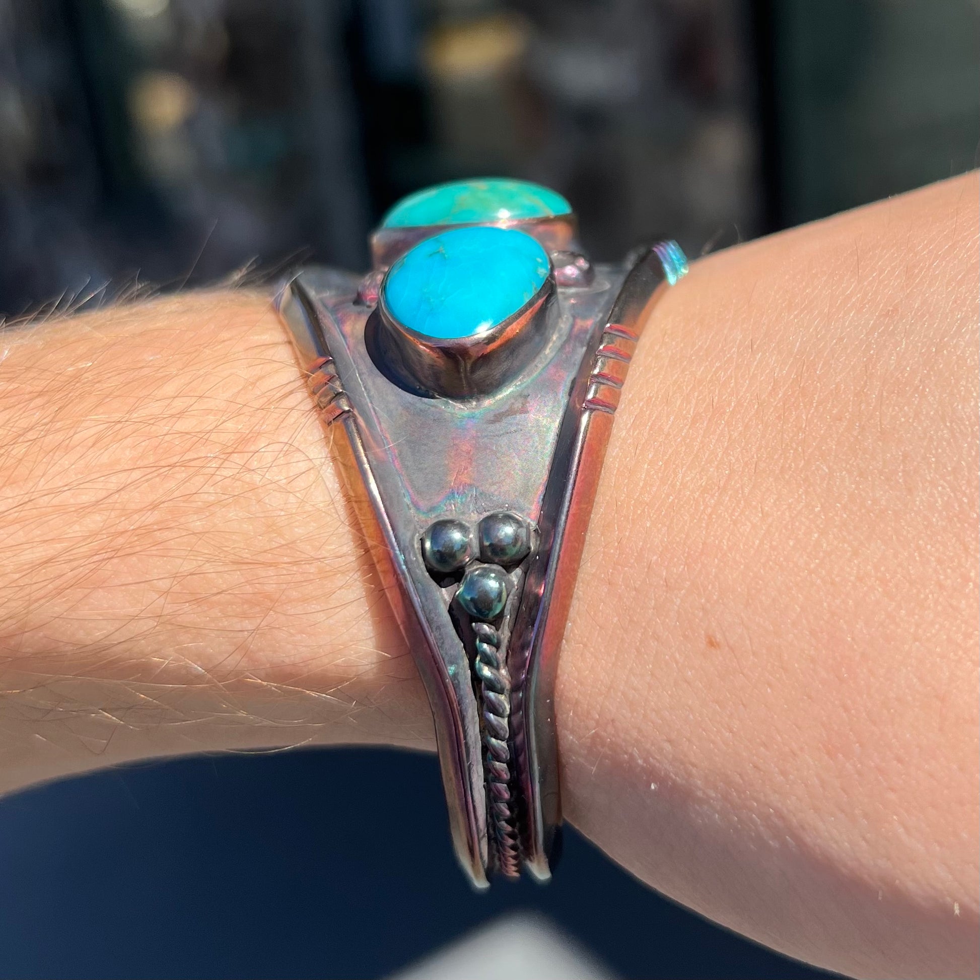 A men's Navajo three stone turquoise cuff bracelet handmade by artist, Dean Brown.  The silver has an iridescent purple patina.